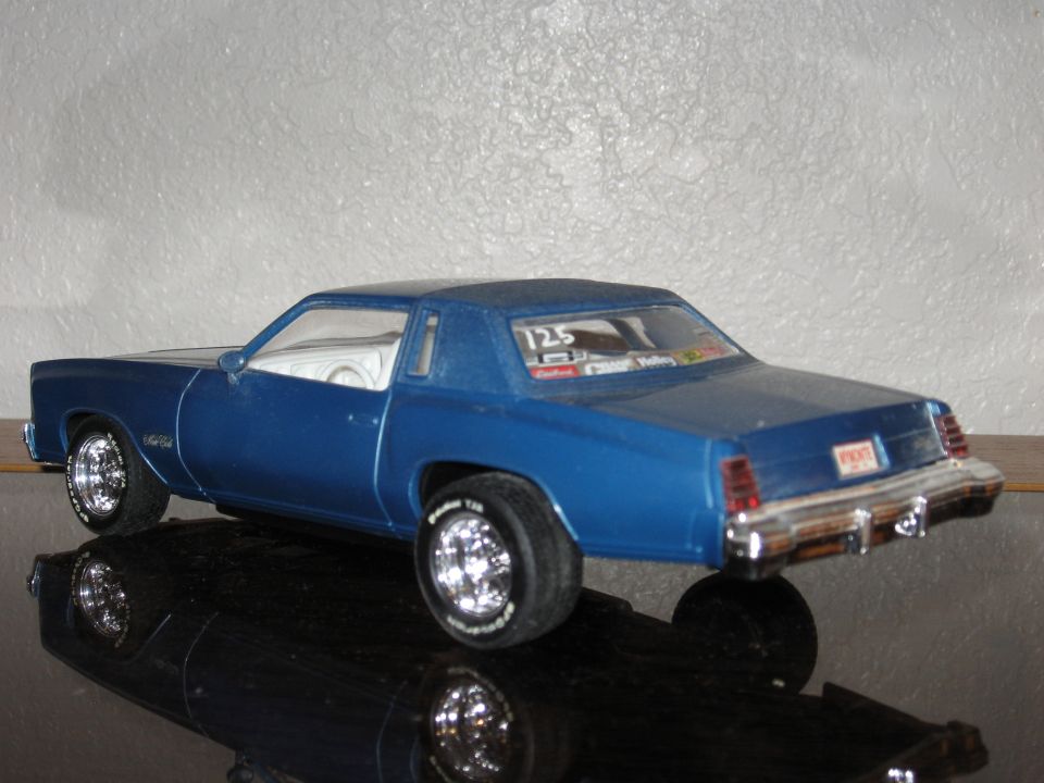 Blue model car with white interior, chrome wheels, and racing decals on the rear window