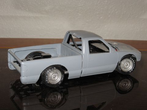 1977 Ford F-150 - Model pickup truck with a roll cage is unpainted and viewed from the rear three-quarter angle.