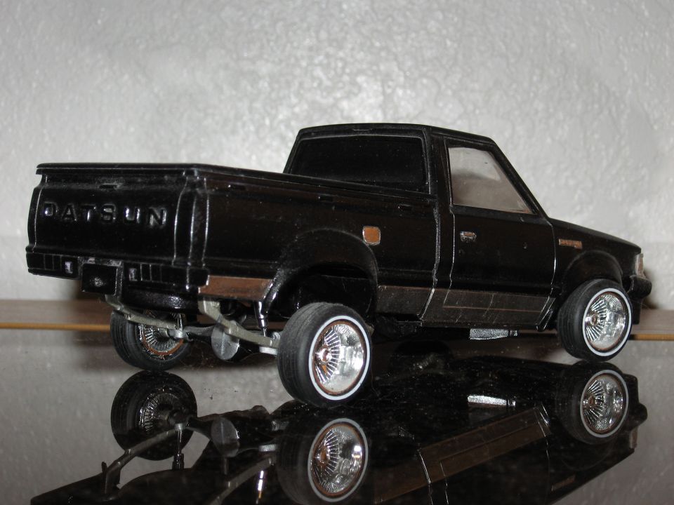 Black Datsun pickup truck model with chrome wheels and a lowered stance