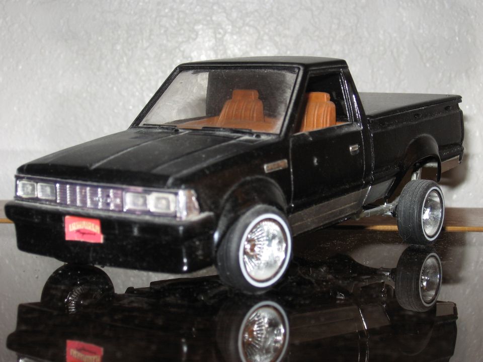 Black pickup truck model with tan interior, chrome grille, and whitewall tires
