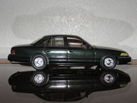 1977 Ford F-150 - A model of a dark green sedan is shown from the side, with its reflection visible below.