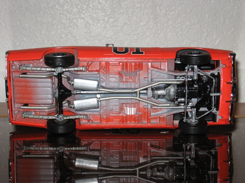 Underside of a red model car with "01" on the roof, showing exhaust and drivetrain components