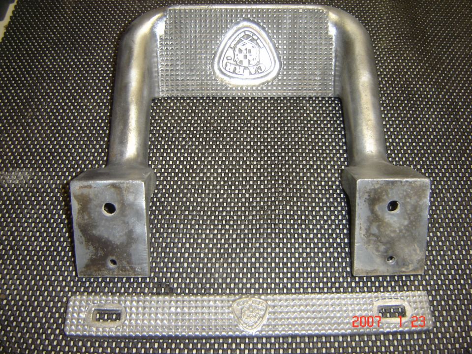 Two metal step plates with a triangular emblem on each. One is a U-shaped handle, the other is a flat bar