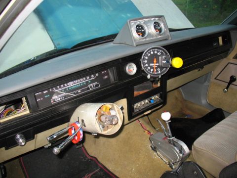 1985 Ford Crown Victoria LTD - The dashboard of a car features a tachometer and other gauges, with the steering column partially disassembled.