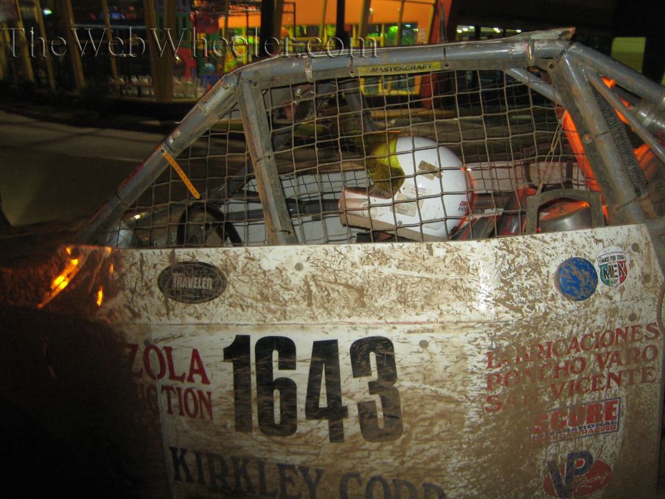 Muddy off-road race truck door numbered 1643 with sponsor decals and caged cab