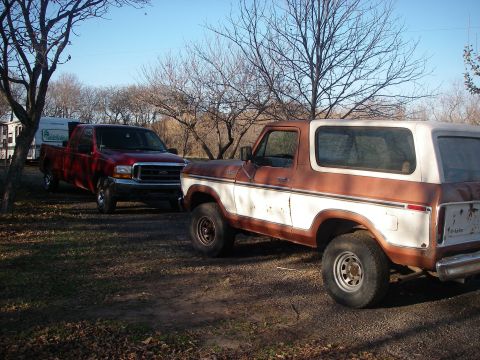1978 Ford Bronco - A two-tone brown and white 1978 Ford Bronco is parked outdoors next to a red pickup truck.