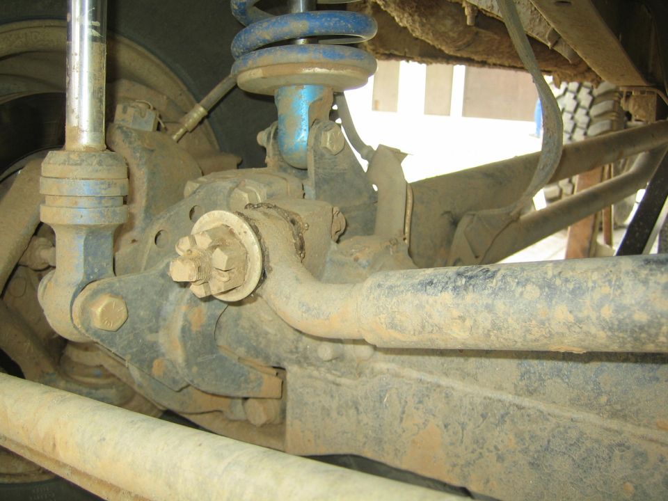Close-up of dusty front suspension, coil spring and axle joint of an off-road vehicle