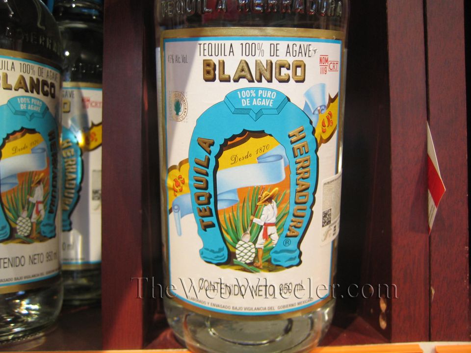 Bottle of Herradura Blanco 100% agave tequila on a shelf with other bottles