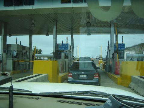 View through windshield of a dark Volkswagen sedan at a toll plaza booth