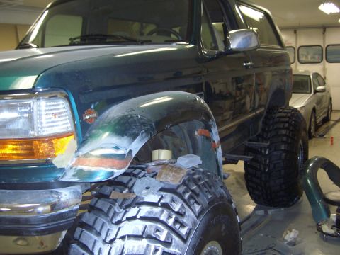 1996 Ford Bronco - A Ford Bronco is being worked on in a garage, with a silver sedan visible in the background.
