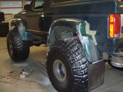 1996 Ford Bronco - A green Ford Bronco with significant fender modifications and oversized tires is shown from the rear quarter angle.