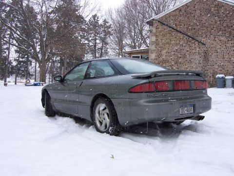 1996 Ford Probe - Rear view of a 1996 Ford Probe covered in snow, parked next to a stone building.
