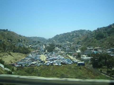 Hillside town packed with parked cars and houses under a clear blue sky