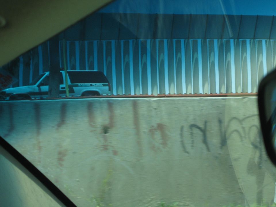 Border Patrol vehicle parked behind a fence seen through a tinted car window