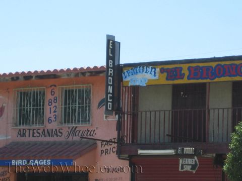 Orange building with 'El Bronco' leather shop and 'Artesanias Mayra' signs