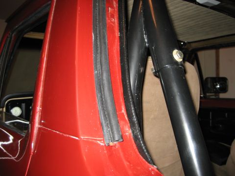 1979 Ford Bronco - Detail shot of the interior door jamb and roll bar structure of a red vehicle.
