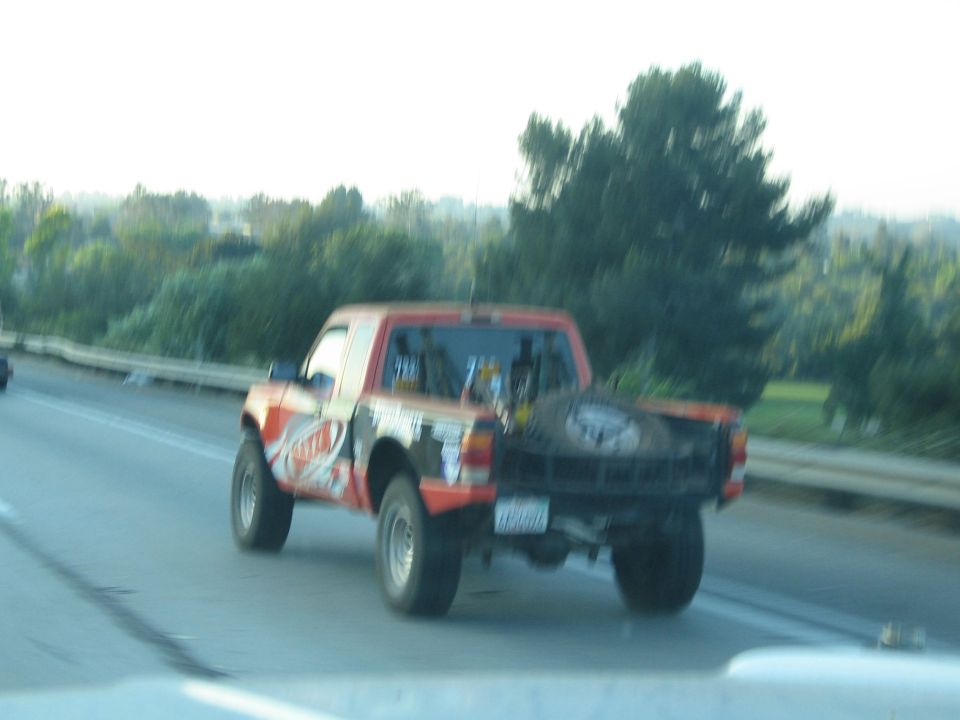 Orange and white off-road race truck driving on a highway
