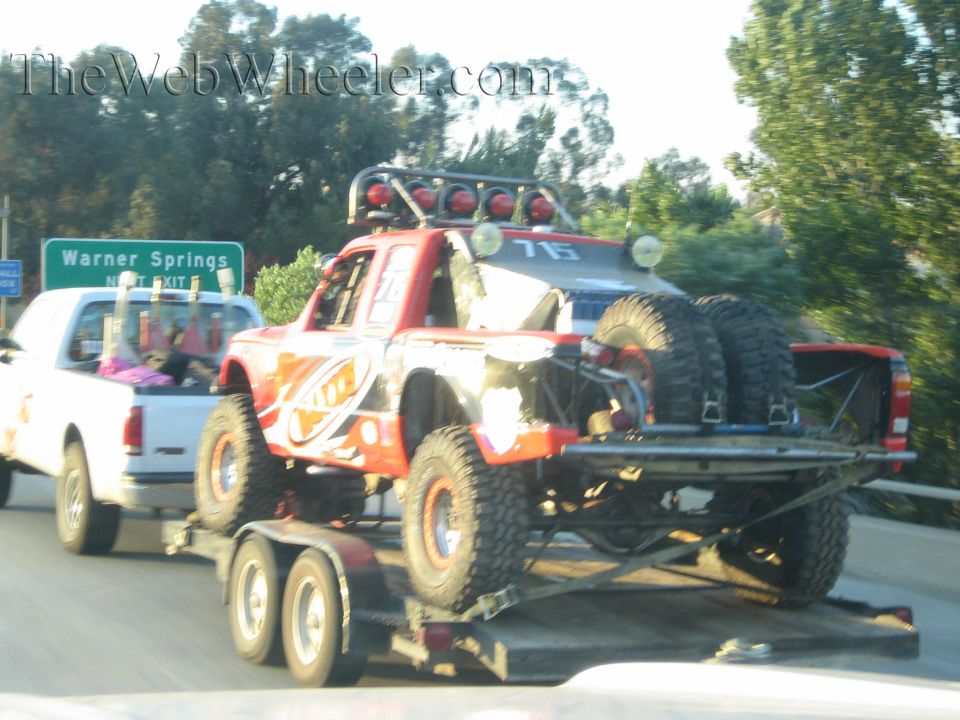 Red off-road race truck number 76 on a trailer near a Warner Springs sign