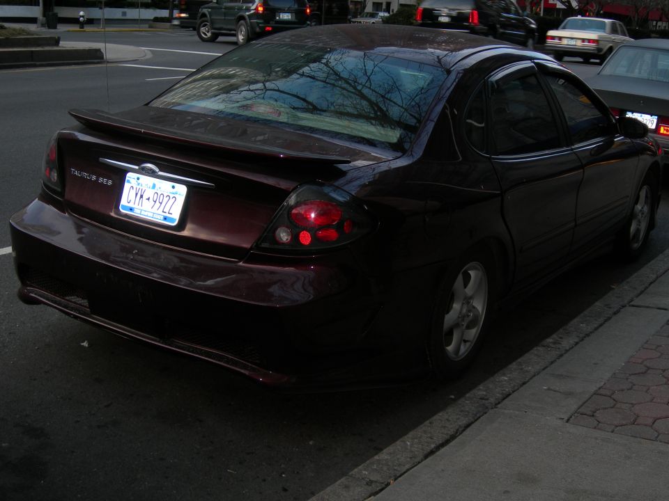 Dark red sedan parked on a street, rear view. License plate CYK-9922. Spoiler on trunk