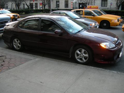 1992 Ford Taurus - A maroon sedan is parked curbside, with other vehicles visible in the background.