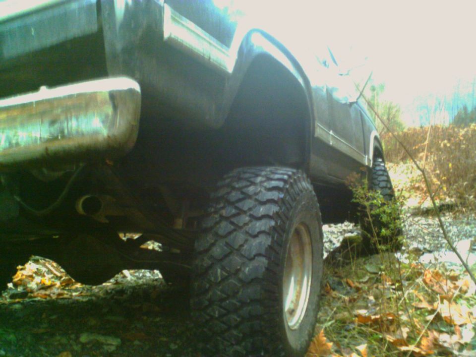 Rear quarter view of a lifted off-road vehicle with large tires and chrome bumper