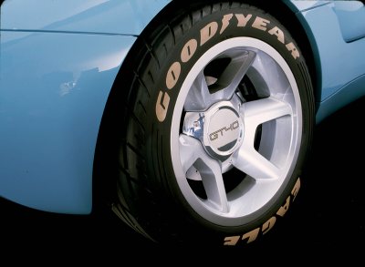 2003 Ford GT - A close-up shot focuses on the wheel and tire of a blue vehicle, Goodyear Eagle branding and a GT40 emblem on the hub.