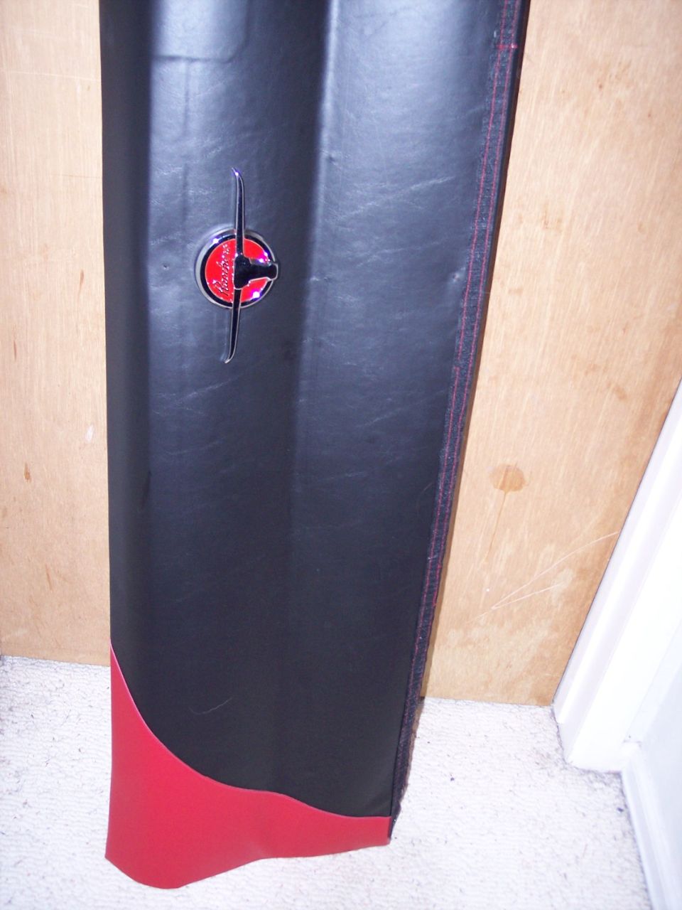 Black and red custom vinyl door panel with chrome window crank leaning against plywood
