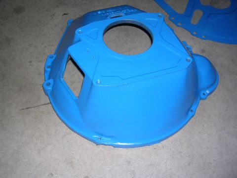 1975 Ford Ranchero - A blue bell housing, likely for a transmission, is shown on a concrete surface. The part features a large central opening and several bolt…