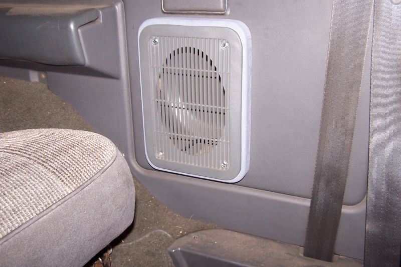 Interior shot of a speaker adapter mounted on a gray panel next to a seat and seatbelt