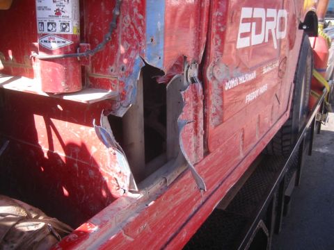 1979 Ford Bronco - Side view of a damaged red truck with the text EDRO and names visible on the panel.