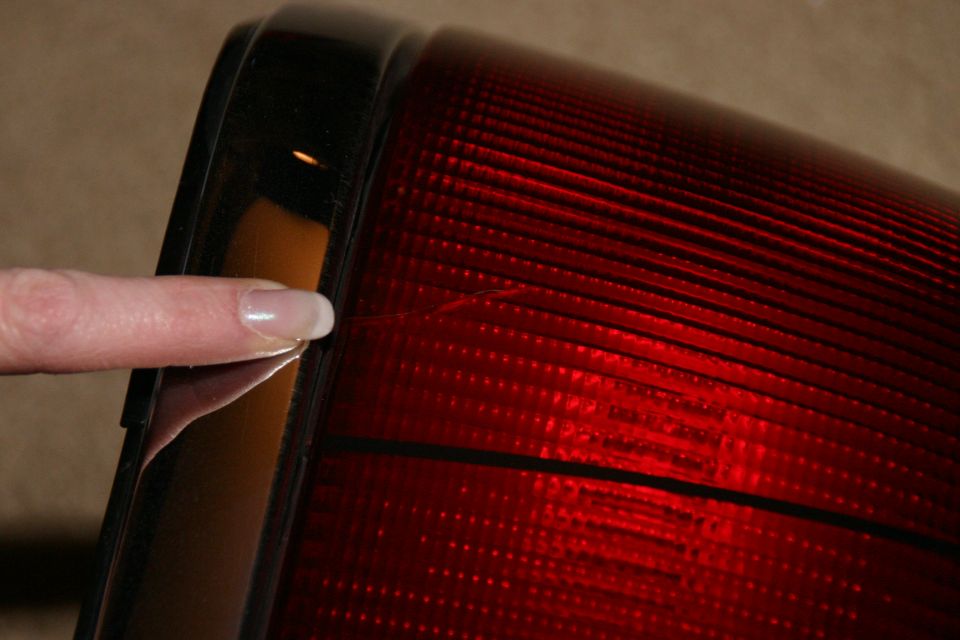 Close-up of a finger touching the edge of a red tail light lens