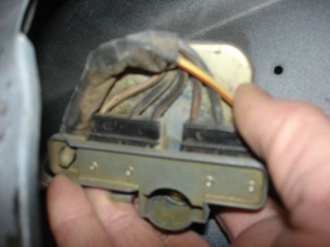 1979 Ford Bronco - A hand manipulates a vehicle's electrical connector, showing wires and a metal housing.