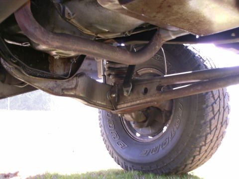 1984 Ford Bronco - This photo shows the undercarriage of a vehicle, focusing on the front suspension components and exhaust pipe.