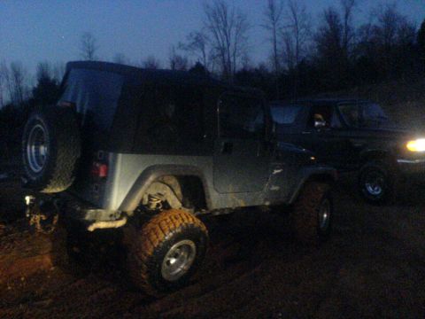 1997 Jeep Wrangler - A 1997 Jeep Wrangler is seen from the rear three-quarter view, with another vehicle visible behind it.
