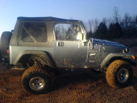 1997 Jeep Wrangler - Side view of a 1997 Jeep Wrangler on a dirt track.