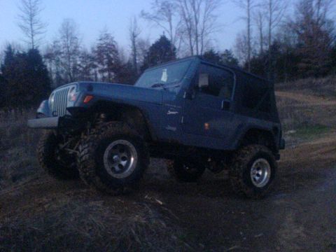 1997 Jeep Wrangler - This Jeep Wrangler is shown off-road with a soft top and large tires.