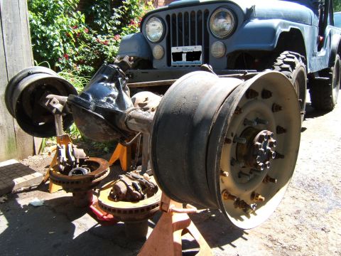 1980 Jeep CJ5 - The front axle and wheels of a Jeep are disassembled and supported by jack stands.