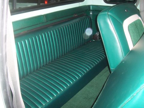1994 Ford F-150 - The interior of a vehicle features a green bench seat with a distinctive ribbed pattern and a contrasting white stripe.