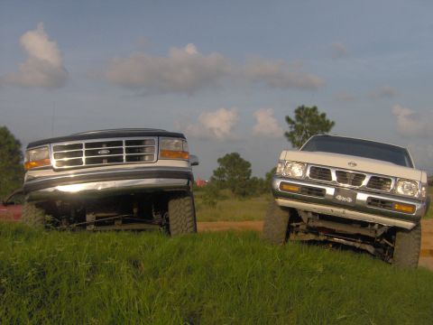 1974 Ford F-100 - Two trucks are positioned on a grassy hill, viewed from the front.