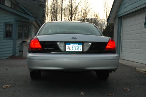 2003 Ford Crown Victoria - The rear of a silver Ford Crown Victoria is parked in a driveway next to a garage.