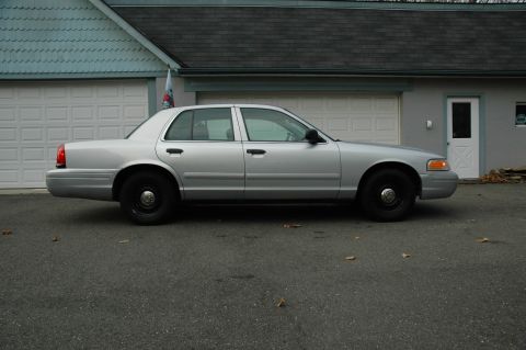 2003 Ford Crown Victoria - Silver 2003 Ford Crown Victoria parked on asphalt in front of a garage with white doors.