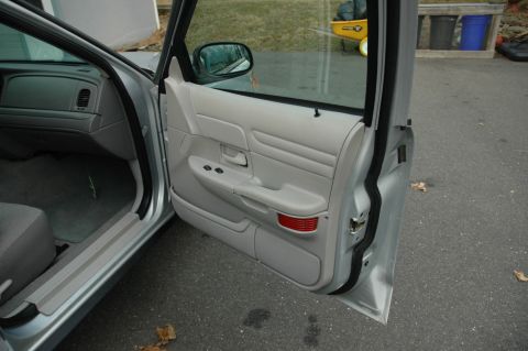 2003 Ford Crown Victoria - The interior door panel and dashboard of a 2003 Ford Crown Victoria are visible with the driver's door open.