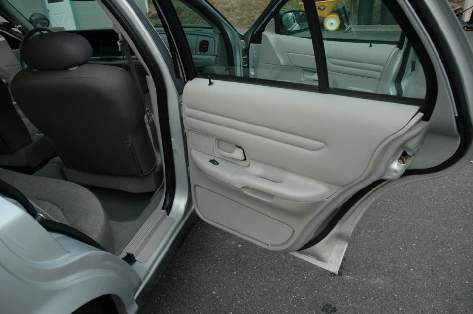 2003 Ford Crown Victoria interior showing front and rear doors open, gray seats and door panels
