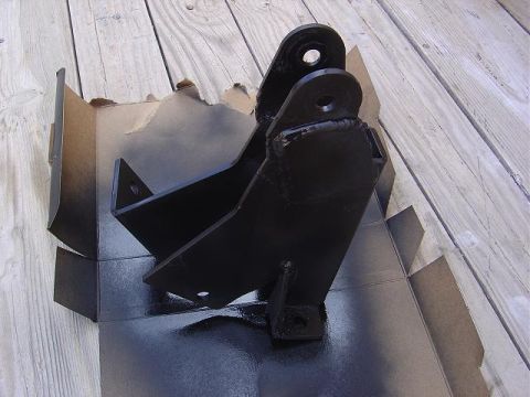 1986 Ford Bronco II - A metal bracket is painted black and placed in a cardboard box on a wooden deck.