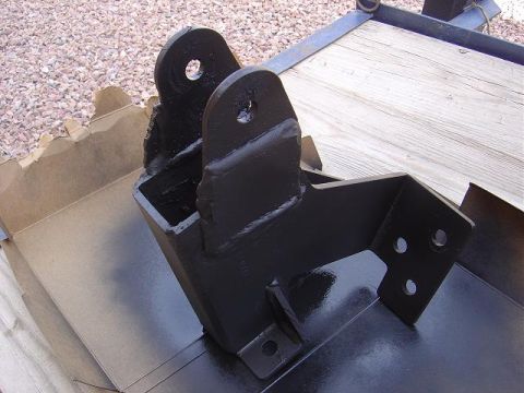 1986 Ford Bronco II - A black metal bracket, likely a vehicle part, is shown in detail against a gravel and trailer background.
