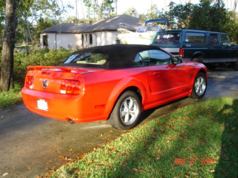 1996 Ford C-150 (Centurion Conversions) - A red convertible sports car is parked in front of a house with other vehicles and a boat in the background.