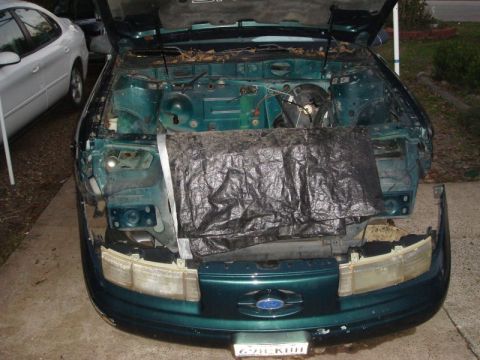 1993 Ford Taurus - Front view of a 1993 Ford Taurus with its hood open and engine bay partially covered.