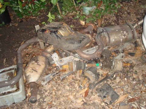 1993 Ford Taurus - Discarded vehicle exhaust components lie scattered amongst leaves and debris.