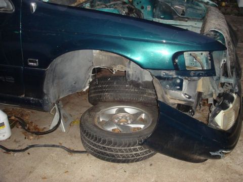 1993 Ford Taurus - Front fender and wheel of a teal 1993 Ford Taurus, showing the DOHC badge and damage to the bumper area.