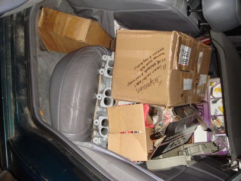 1993 Ford Taurus - Interior of a car filled with boxes and an engine part, likely being transported.